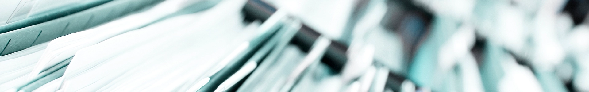 Close-up of stacked file folders arranged in a row with a soft, blurred teal and white background.