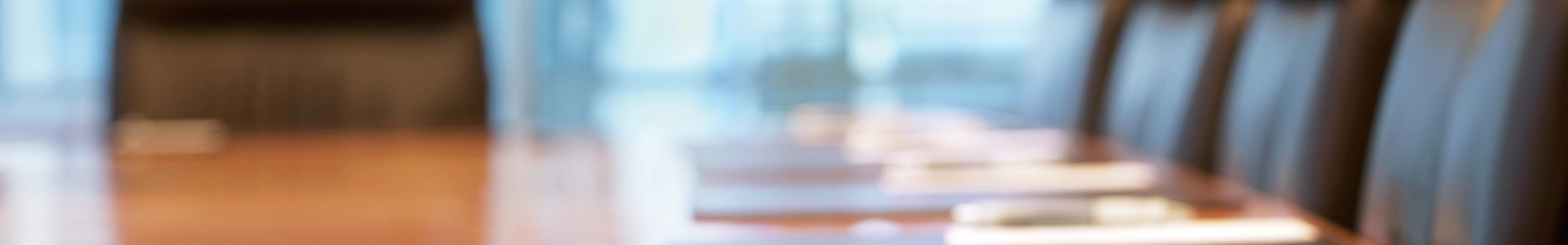 Blurred view of a conference room table with chairs and documents arranged for a meeting.