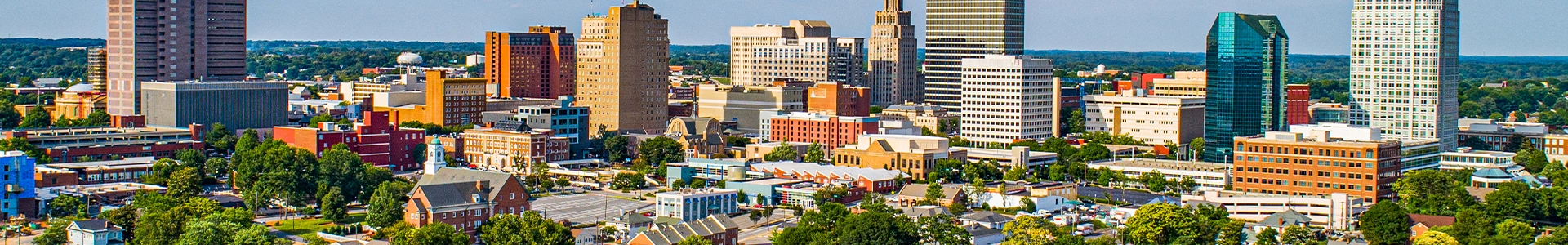 Aerial panoramic view of downtown Winston‑Salem showcasing high‑rise buildings, historic architecture, and tree‑lined streets.